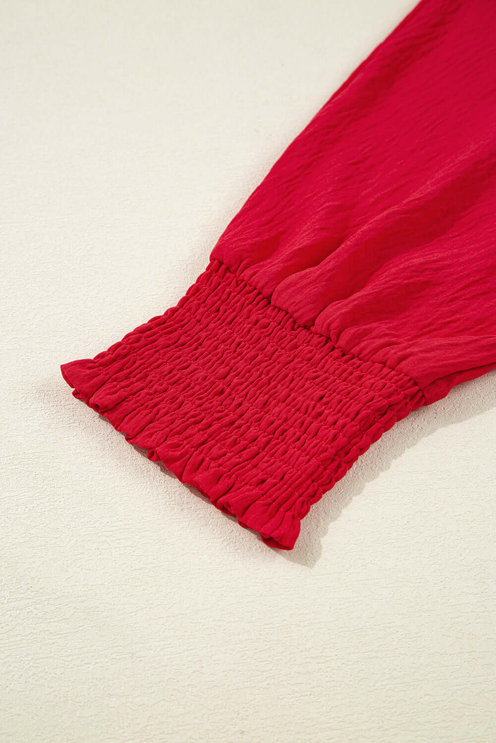 Close-up of the shirred sleeve of the TRUE PASSION TOP in fiery red, highlighting its stylish design and comfort.