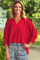 Woman wearing a TRUE PASSION TOP in fiery red with oversized fit and collared detail, paired with checkered pants.