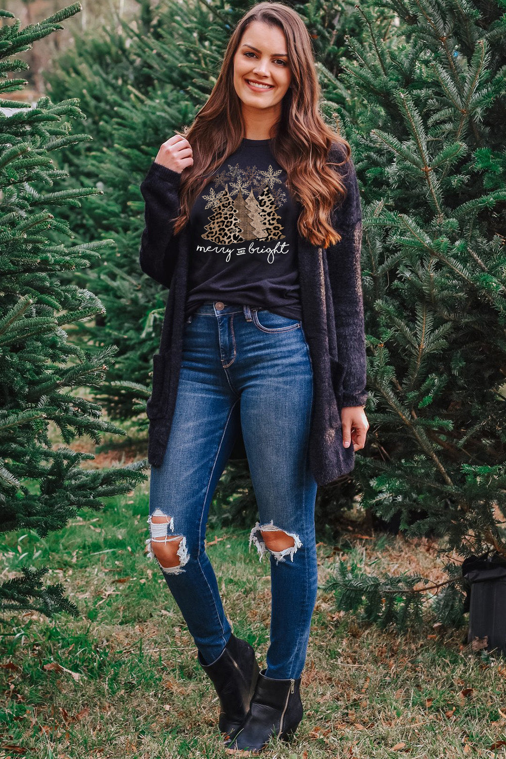 Model wearing Merry & Bright Leopard Tee with festive Christmas tree graphic in a holiday setting.