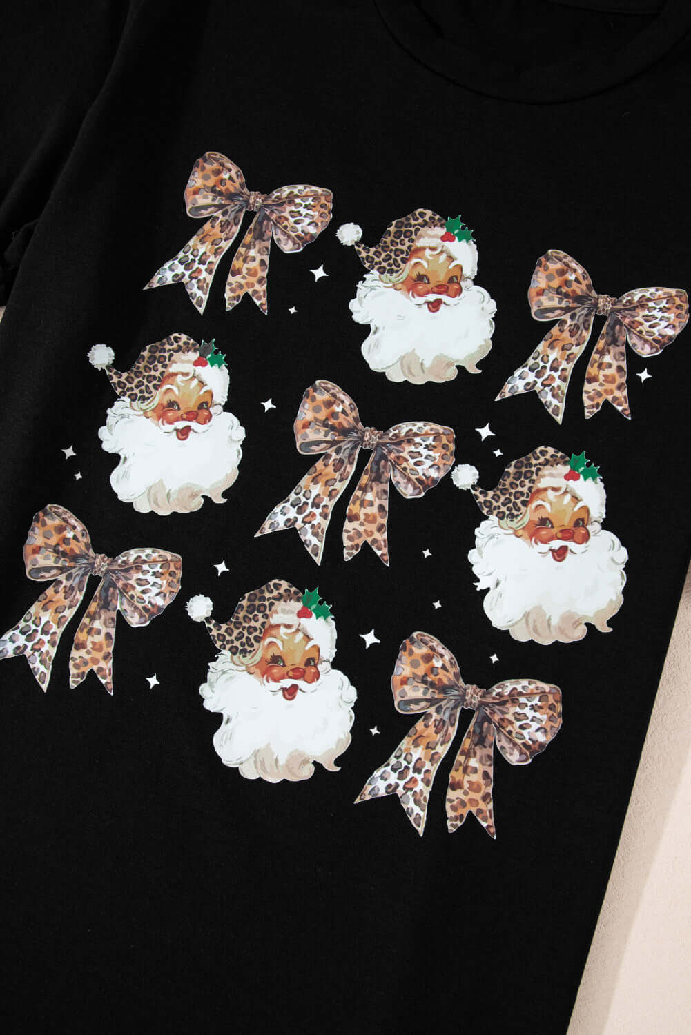 Festive black T-shirt featuring playful Santa graphics and leopard print bows, perfect for holiday celebrations.