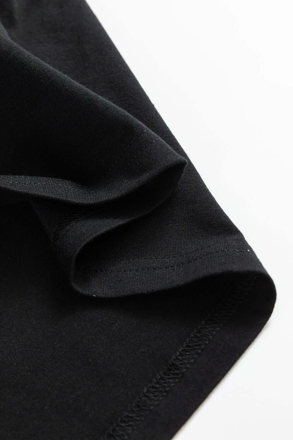 Close-up of the soft fabric and rolled sleeve of a black T-shirt.