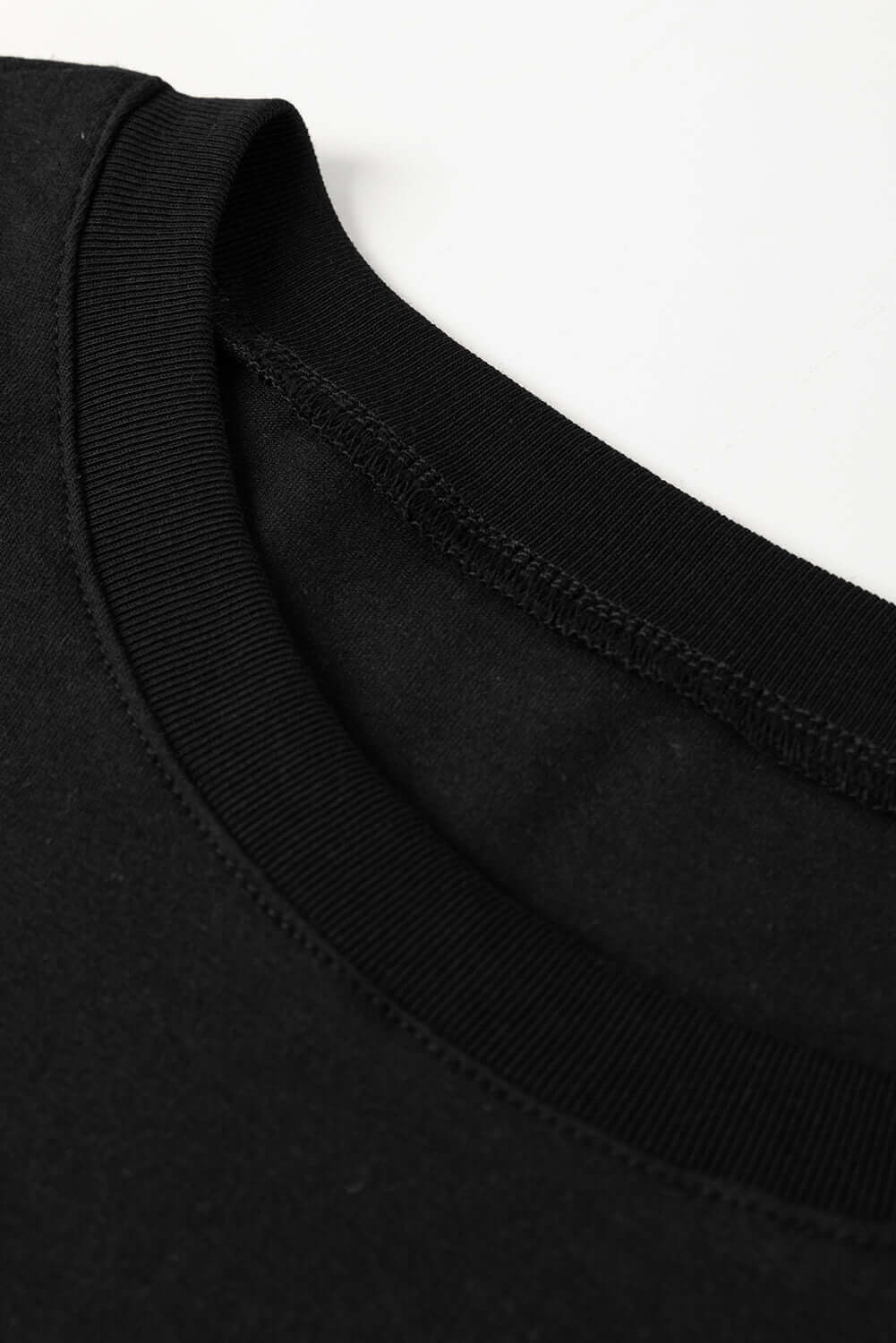 Close-up of black tee's neckline with ribbed collar, showcasing soft fabric and relaxed fit detailing.