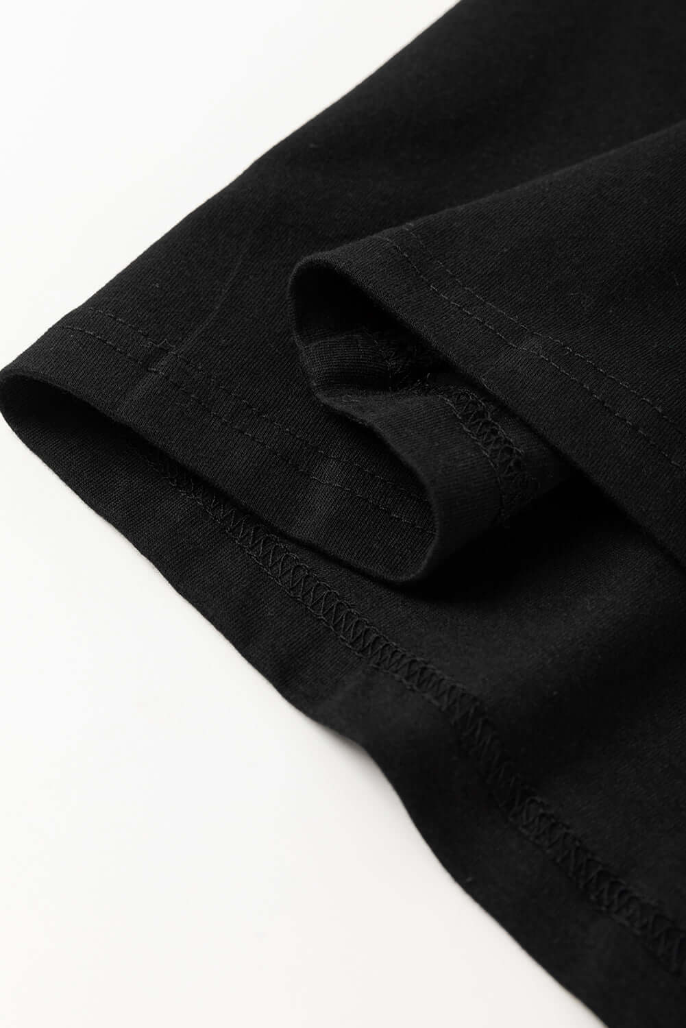 Close-up of the hem and sleeve of a black casual tee featuring a soft and relaxed fit.