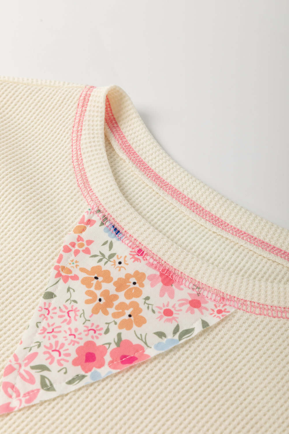 Detail view of the beige waffle knit top with floral accents, showcasing its charming countryside style.