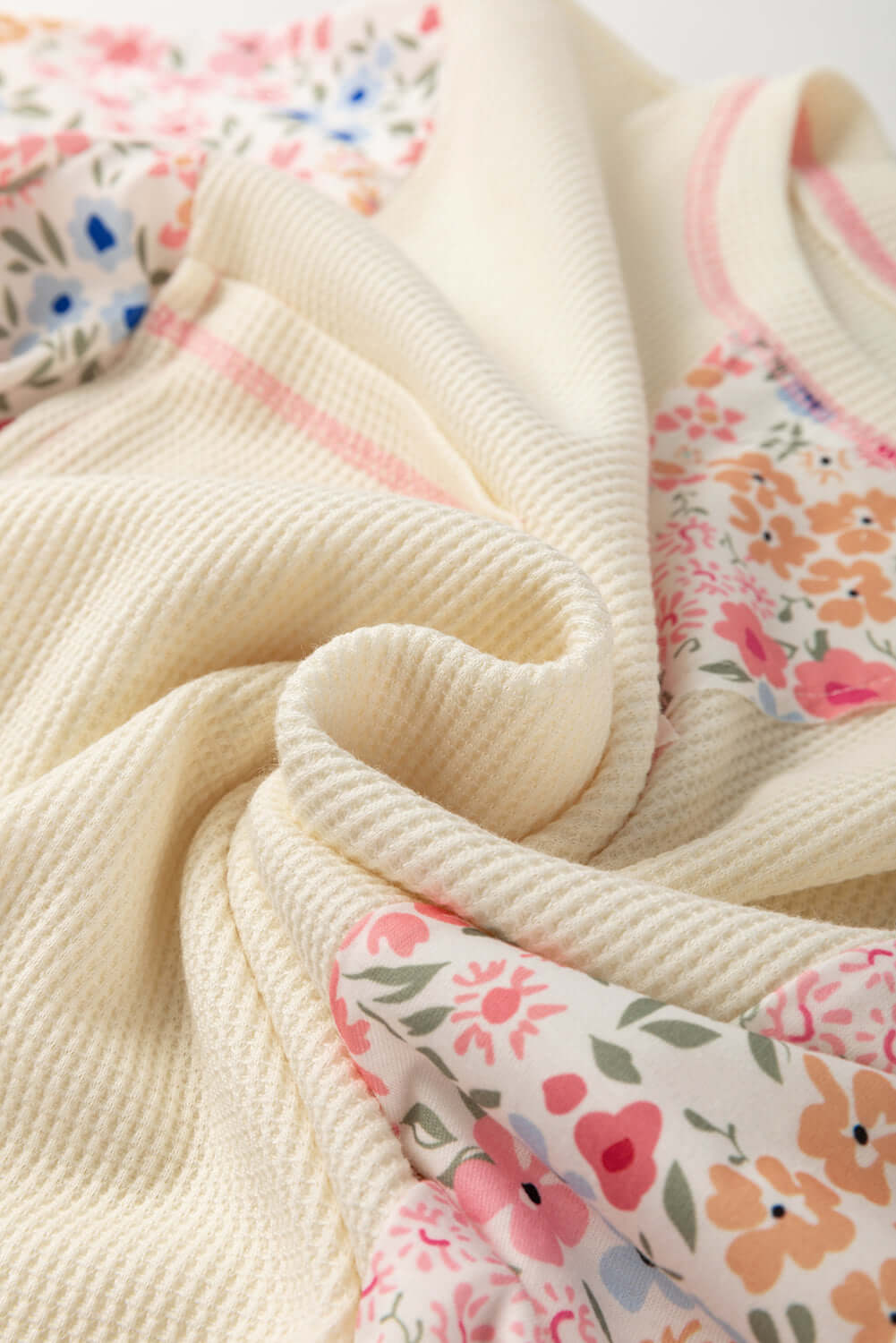 Beige waffle knit top with floral accents, perfect for casual wear in sunny gardens.