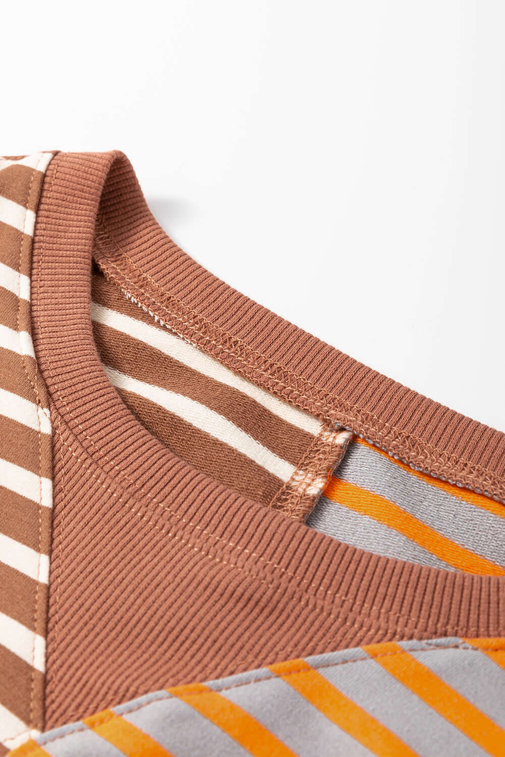 Close-up of the collar design of the MAPLE CIDER CREWNECK TOP showcasing brown and stripe colorblock patterns.