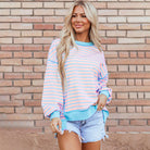 Model wearing a SALTWATER TAFFY TOP with pink and aqua stripes, showcasing a stylish high-low pullover look.