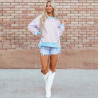 SALTWATER TAFFY TOP styled with denim shorts and white boots against a brick wall, showcasing pink and aqua stripes.