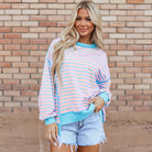 Model wearing SALTWATER TAFFY TOP, showcasing soft pink and aqua stripes with contrast trim, styled with shorts.