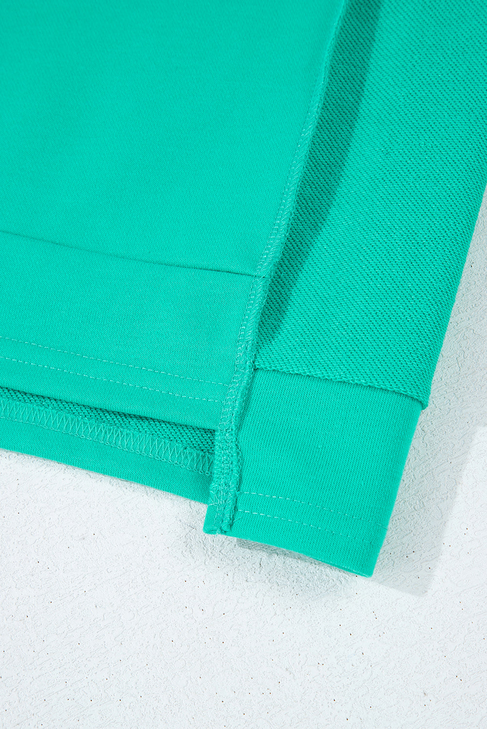 Close-up of the sleek teal We Meet Again Crewneck sweatshirt showcasing its unique splicing details.