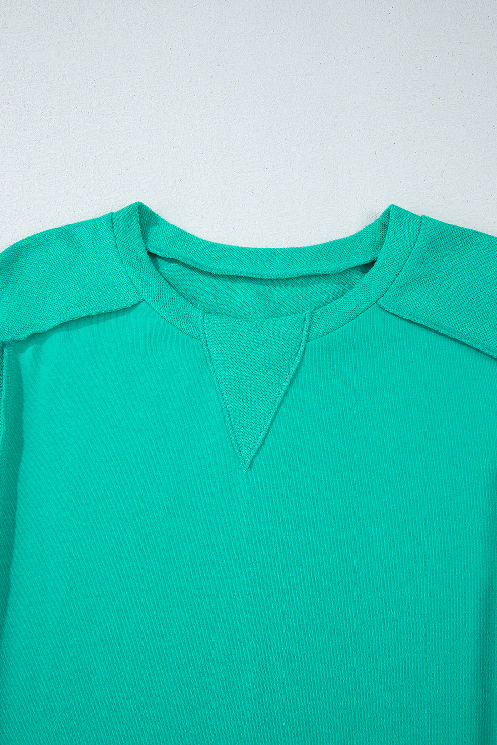 Close-up of teal We Meet Again Crewneck sweatshirt featuring a round neck and splicing detail.