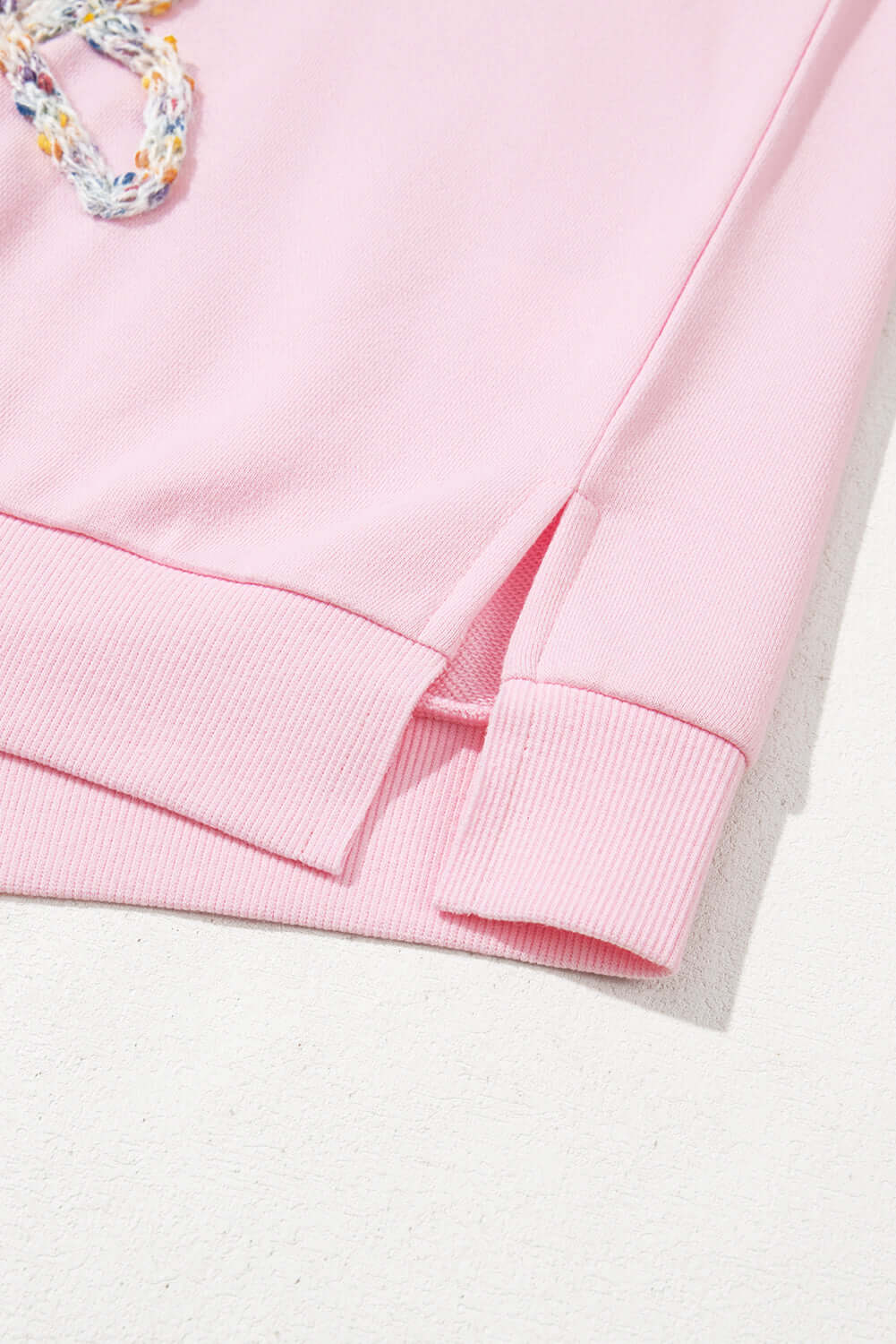 THE BOWTIQUE Top (pink) showing baby pink fabric with embroidered bows and unique split hem design.
