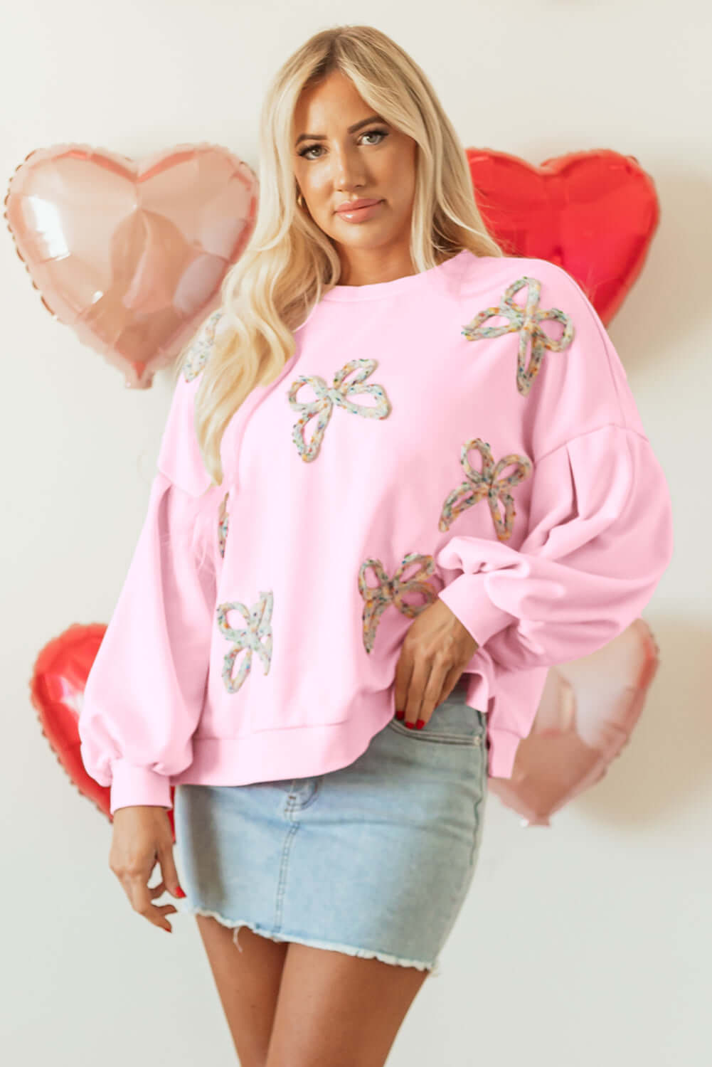 THE BOWTIQUE Top (pink) with embroidered bows, lantern sleeves, styled with a denim skirt and heart balloons.