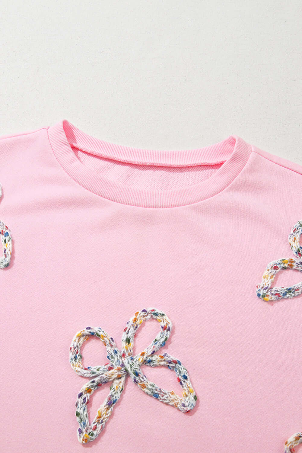 THE BOWTIQUE Top (pink) featuring embroidered bows on a baby pink pullover with a cozy neckline.