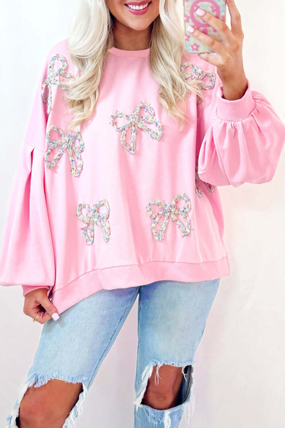 THE BOWTIQUE Top (pink) featuring embroidered bows and lantern sleeves, styled with distressed denim jeans.