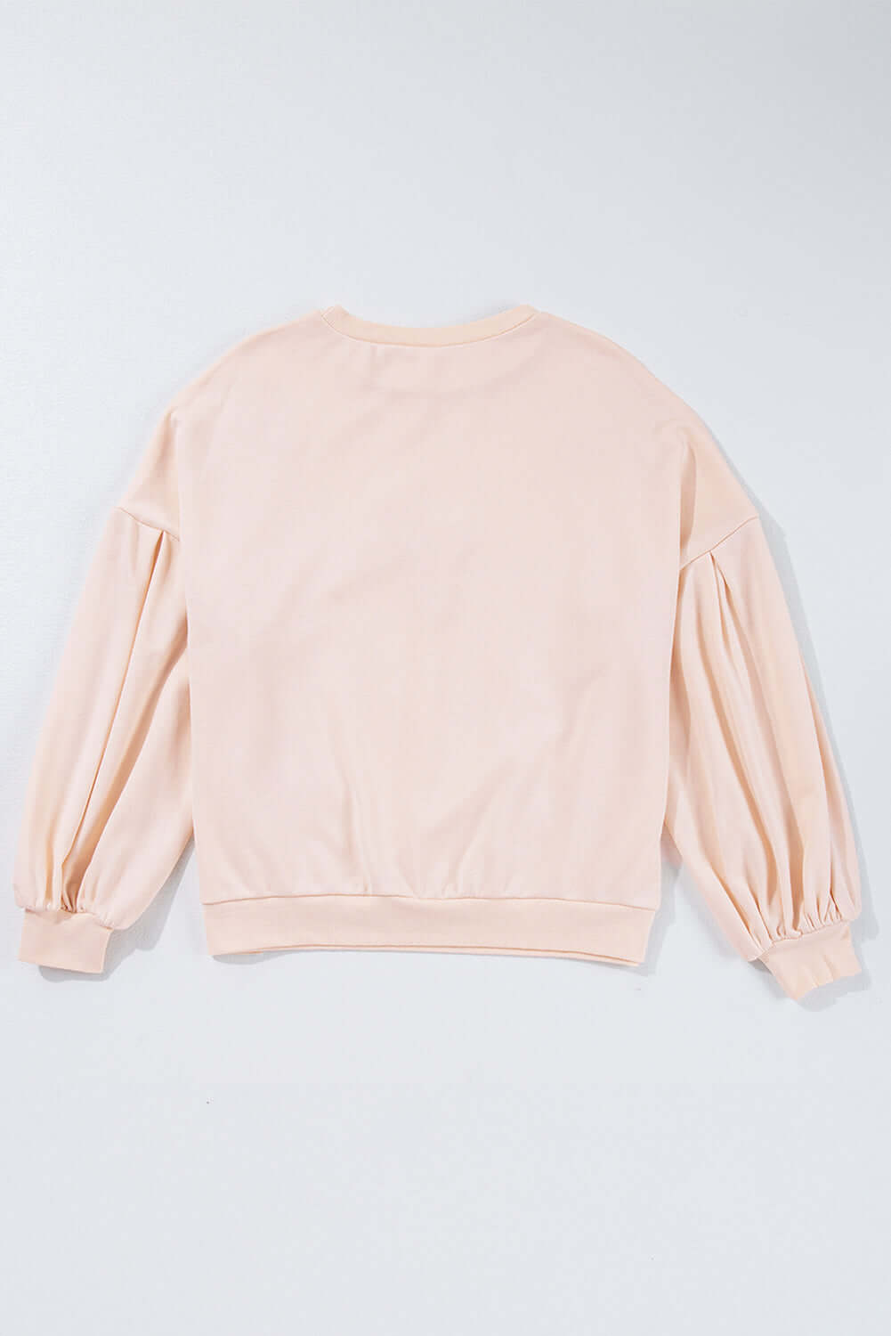 Back view of The Bowtique Top in beige, featuring lantern sleeves and a relaxed fit, perfect for casual wear.