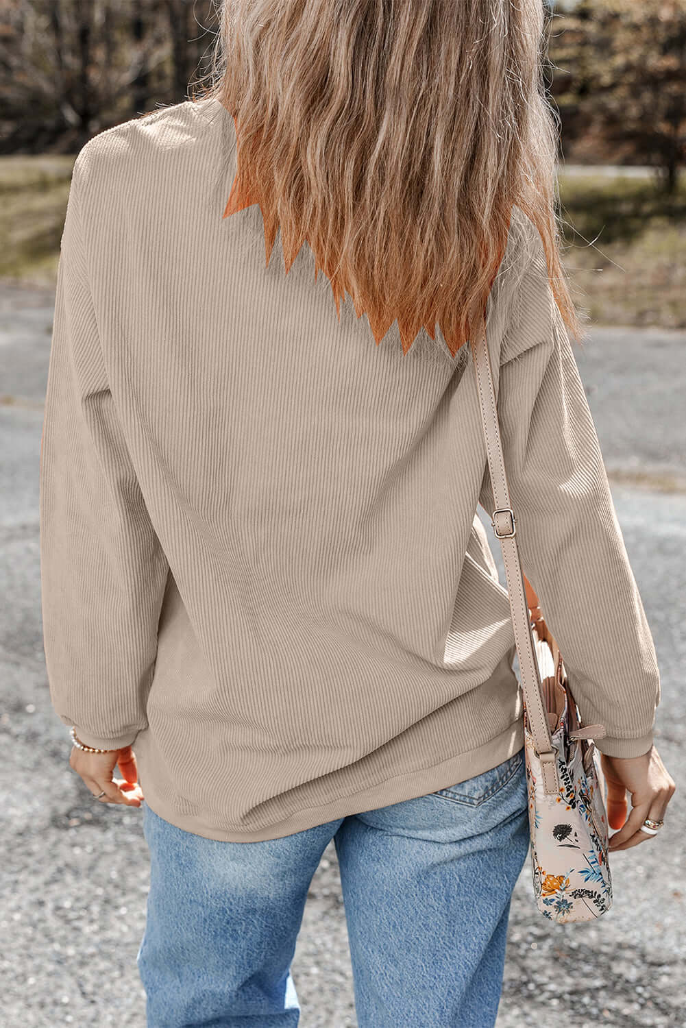 Woman wearing LOVE OF THE GAME CORDED CREW in Harvest Beige with casual jeans and a floral crossbody bag.