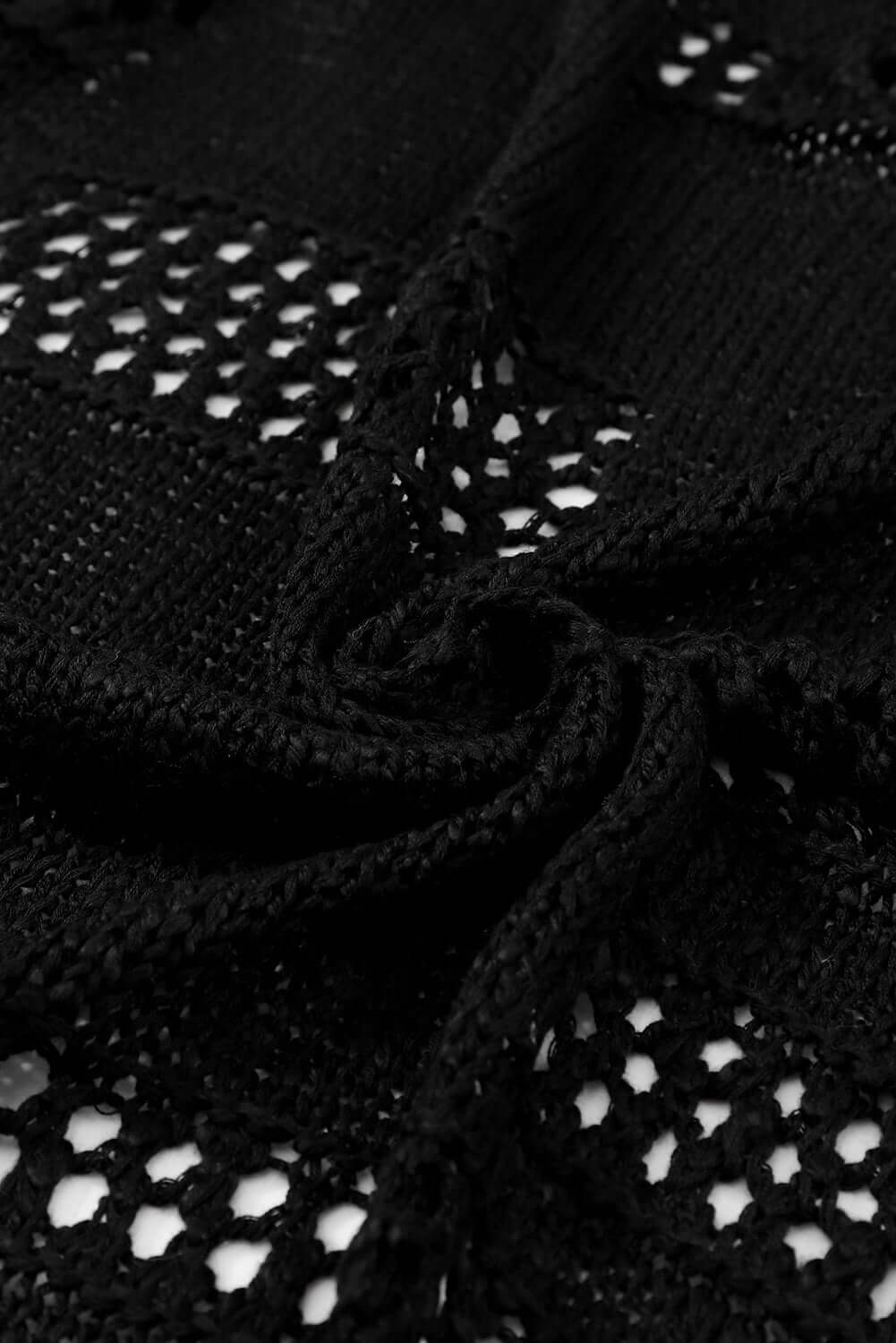 Close-up of lightweight black cable-knit fabric showcasing open stitches and texture for the Blackout Bliss Cardigan.