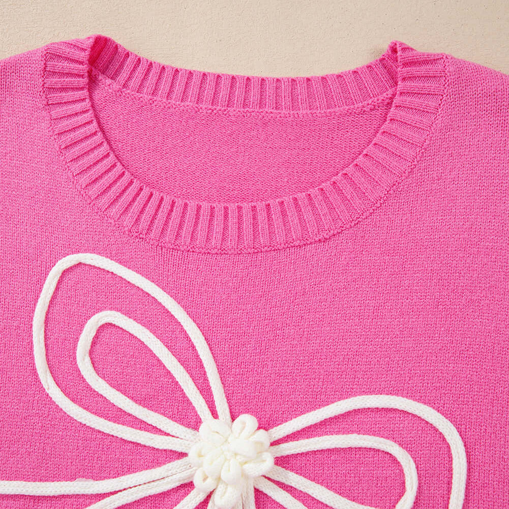 Close-up of the TRIP TO REMEMBER Sweater featuring a pink knit and white corded bow detail.