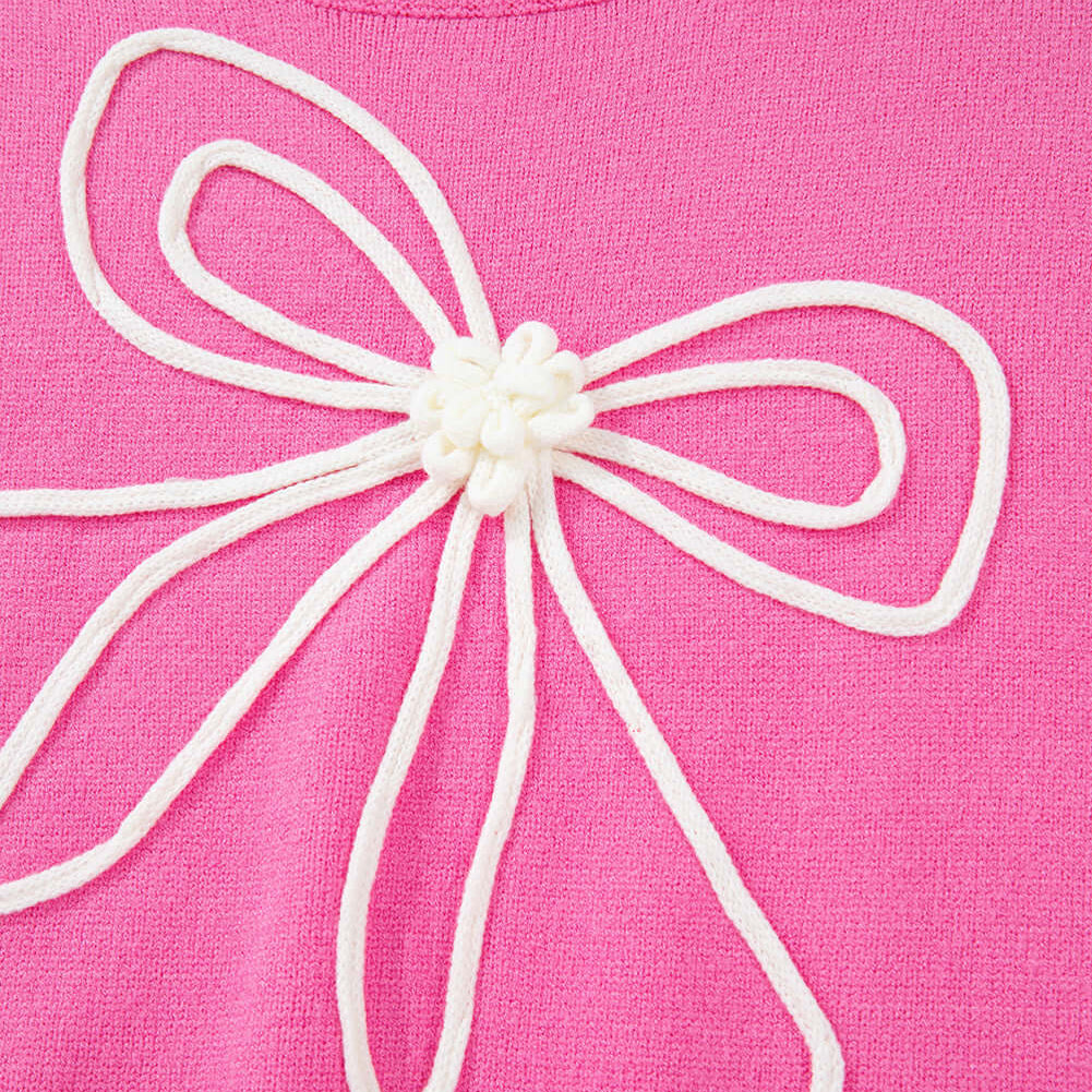 Close-up of a TRIP TO REMEMBER Sweater featuring a corded bow accent on a pink knit fabric.