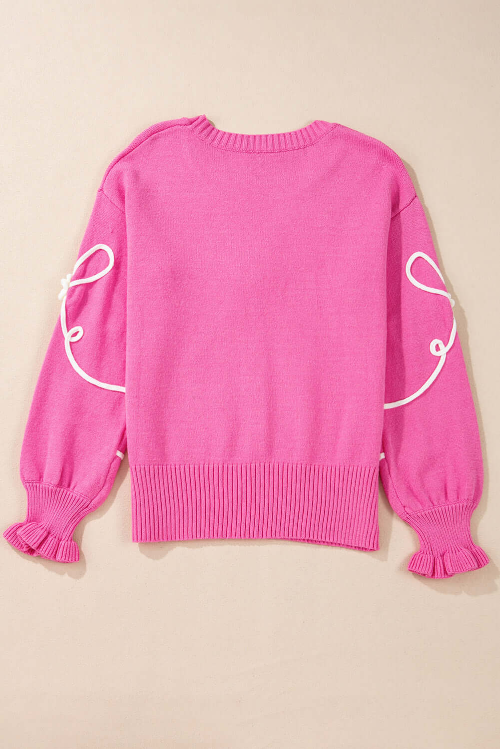 Soft pink TRIP TO REMEMBER sweater with corded bows and ruffled cuffs, perfect for comfort and style.