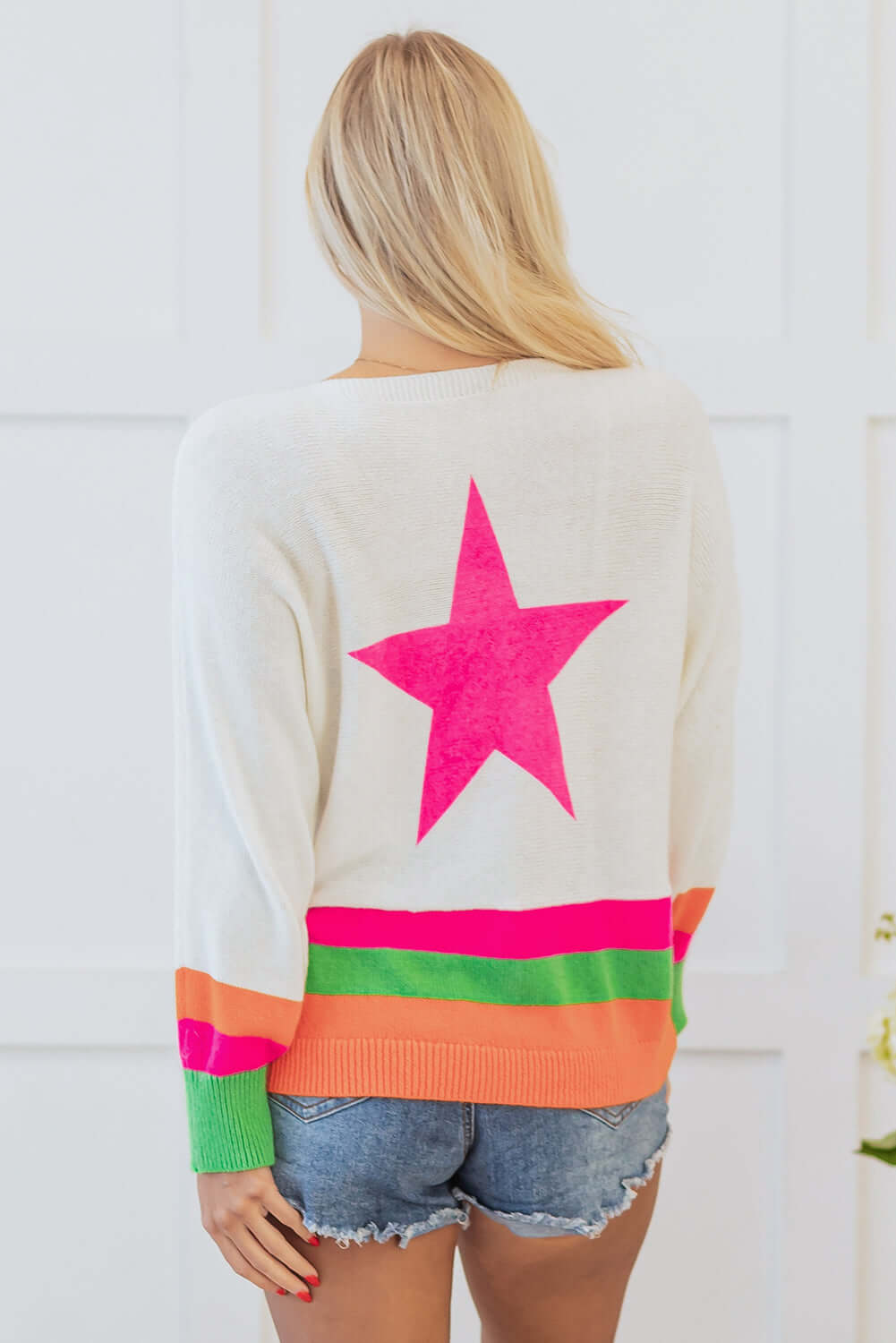 Model wearing STARSTRUCK SWEATER showing bright pink star and colorful striped edges.