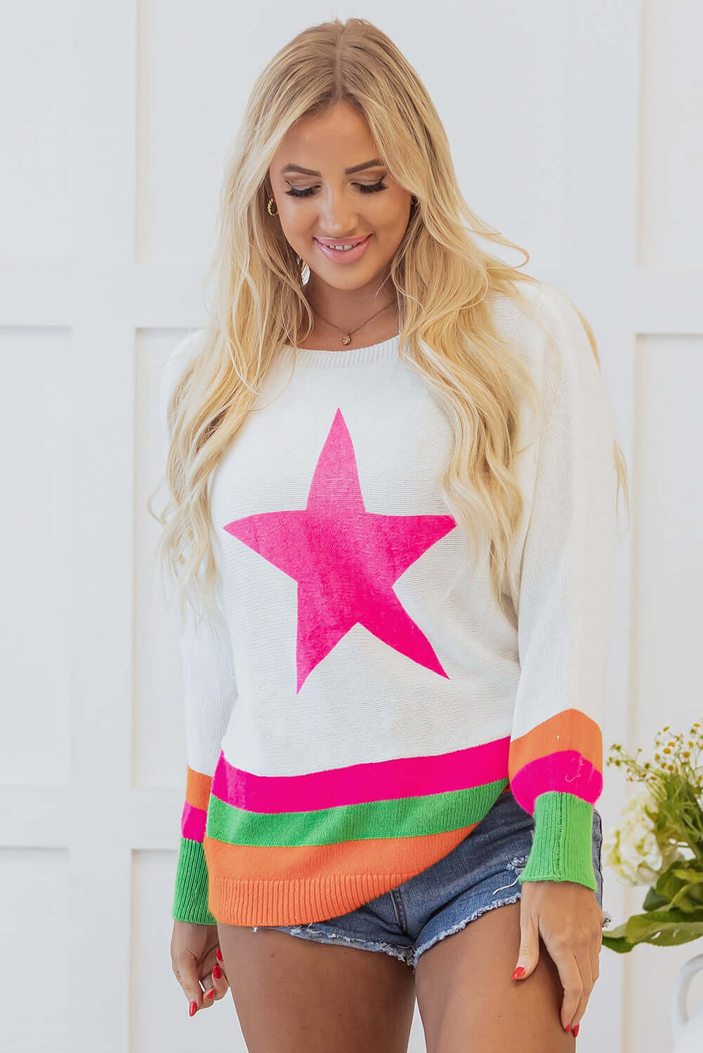 STARSTRUCK SWEATER featuring a playful star design and vibrant colorblock edges, styled with shorts and a cheerful smile.