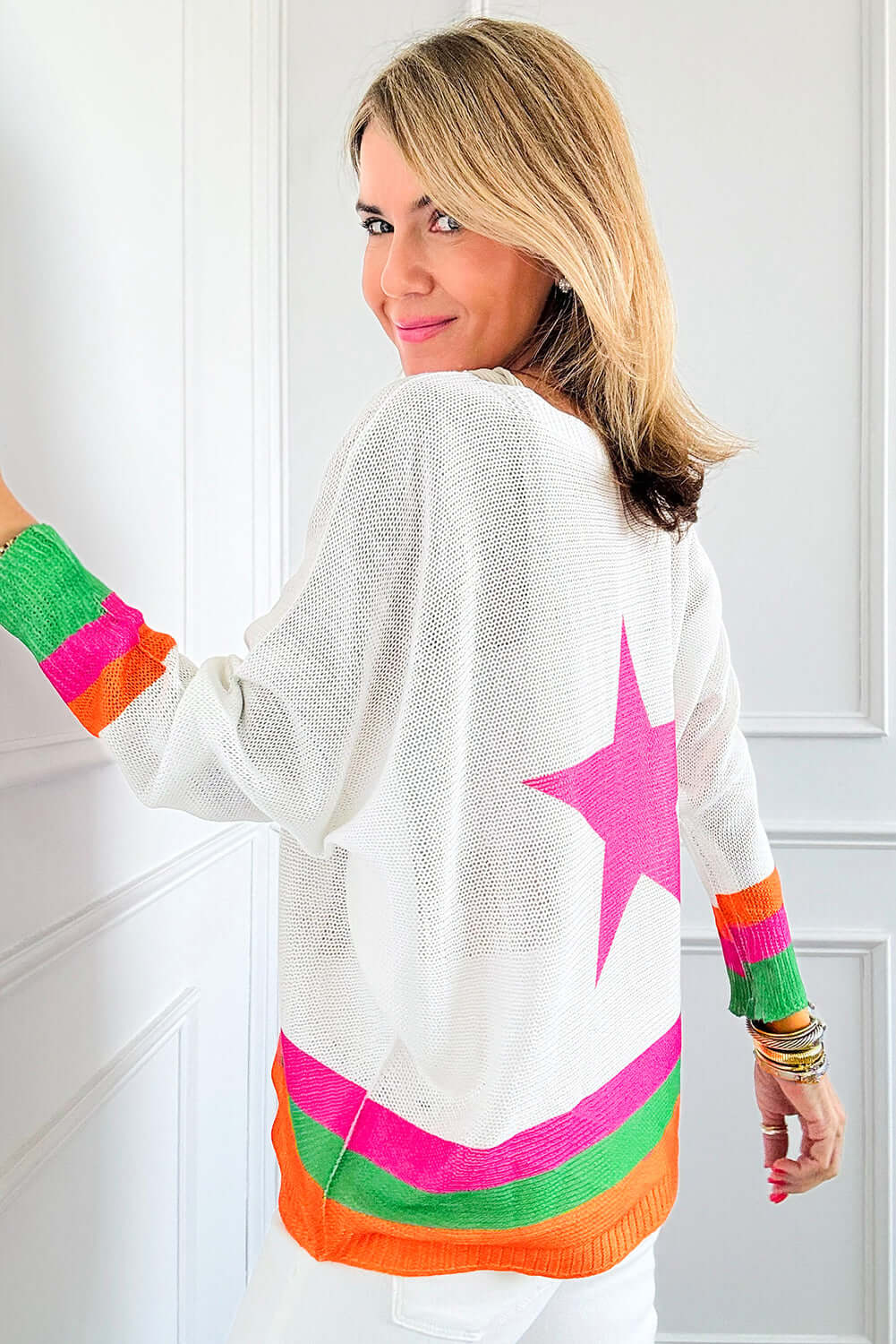 Back view of a model wearing the STARSTRUCK SWEATER, featuring a vibrant colorblock design and a large pink star.