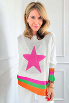 Model wearing STARSTRUCK SWEATER with bold pink star and colorful stripes against a white background.