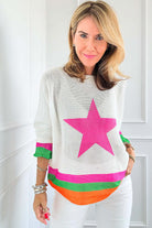 Woman wearing a STARSTRUCK SWEATER with a bold pink star and vibrant colorblock stripes.