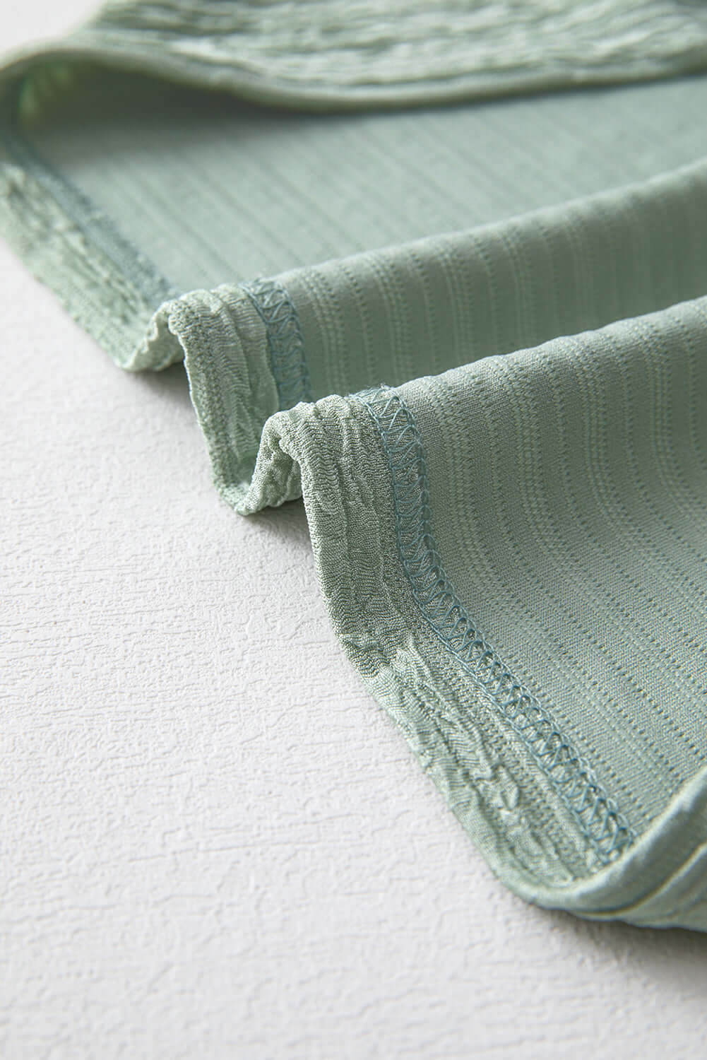 Close-up of the soft sage green crinkle-textured fabric of the Minted Moments Dress, showcasing its unique knit design.