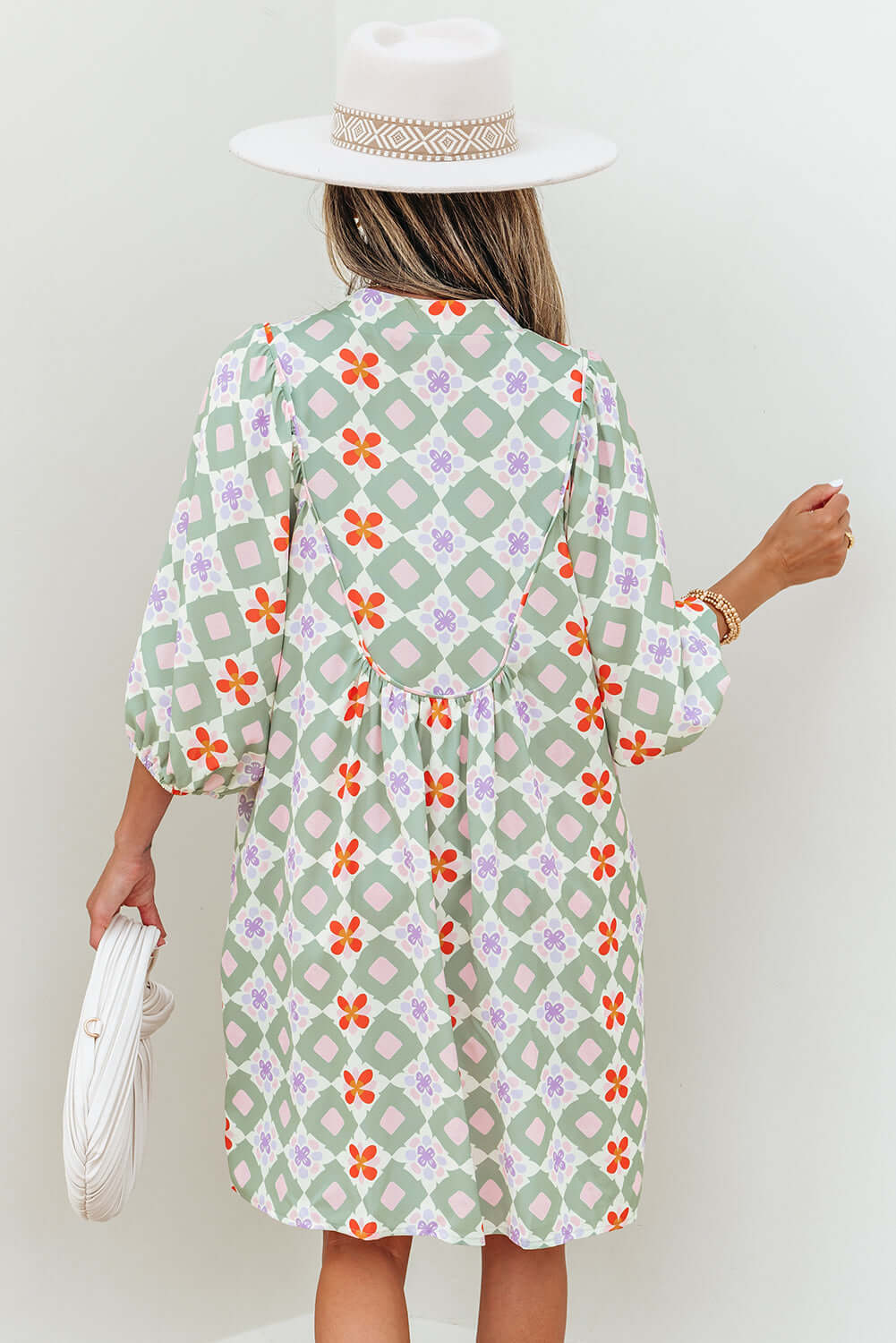 Back view of a woman in a mint mosaic dress featuring a green floral pattern and 3/4 puff sleeves.