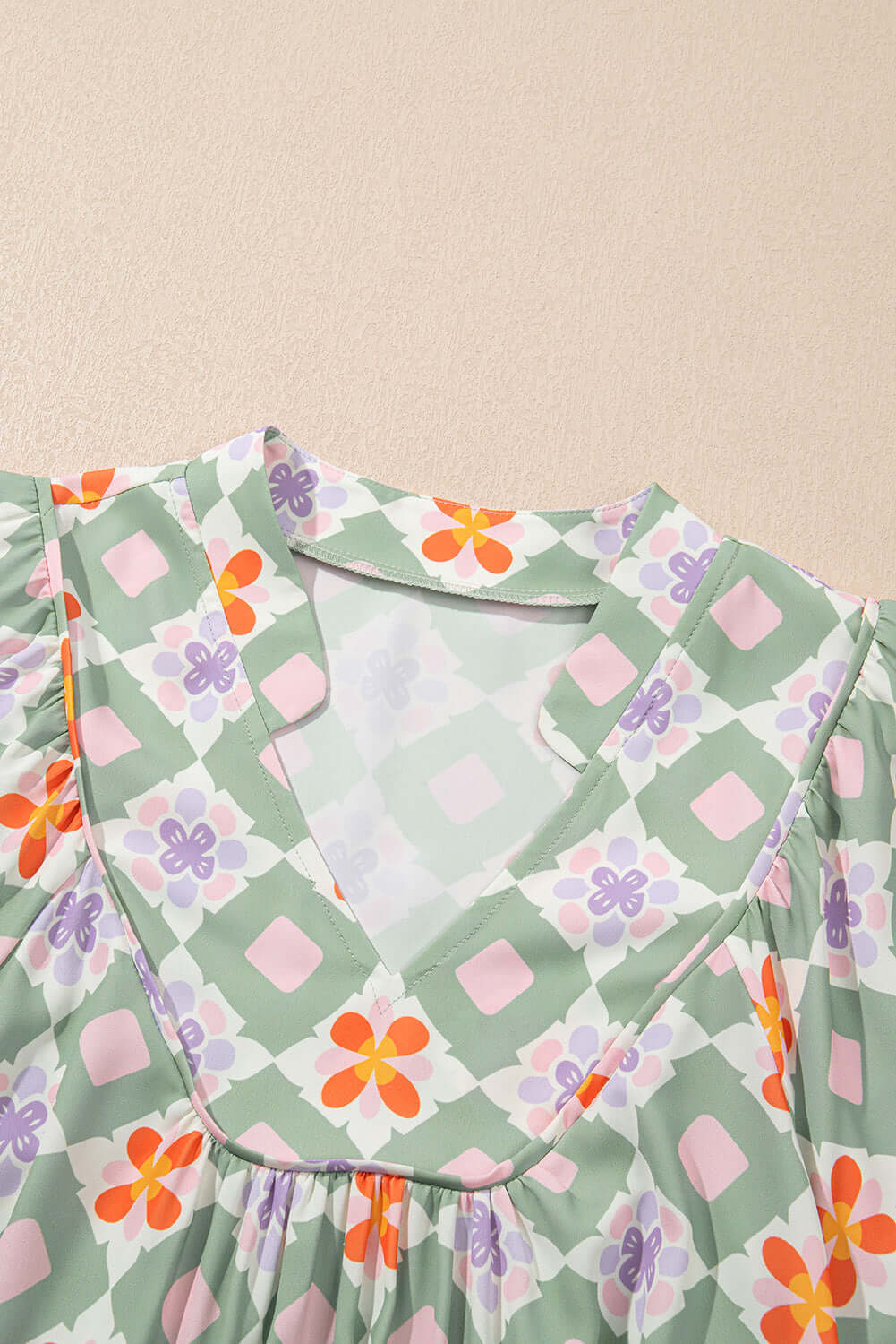 Close-up of the Mint Mosaic Dress featuring a notched V-neck and floral geometric print in mint green, pink, and orange.