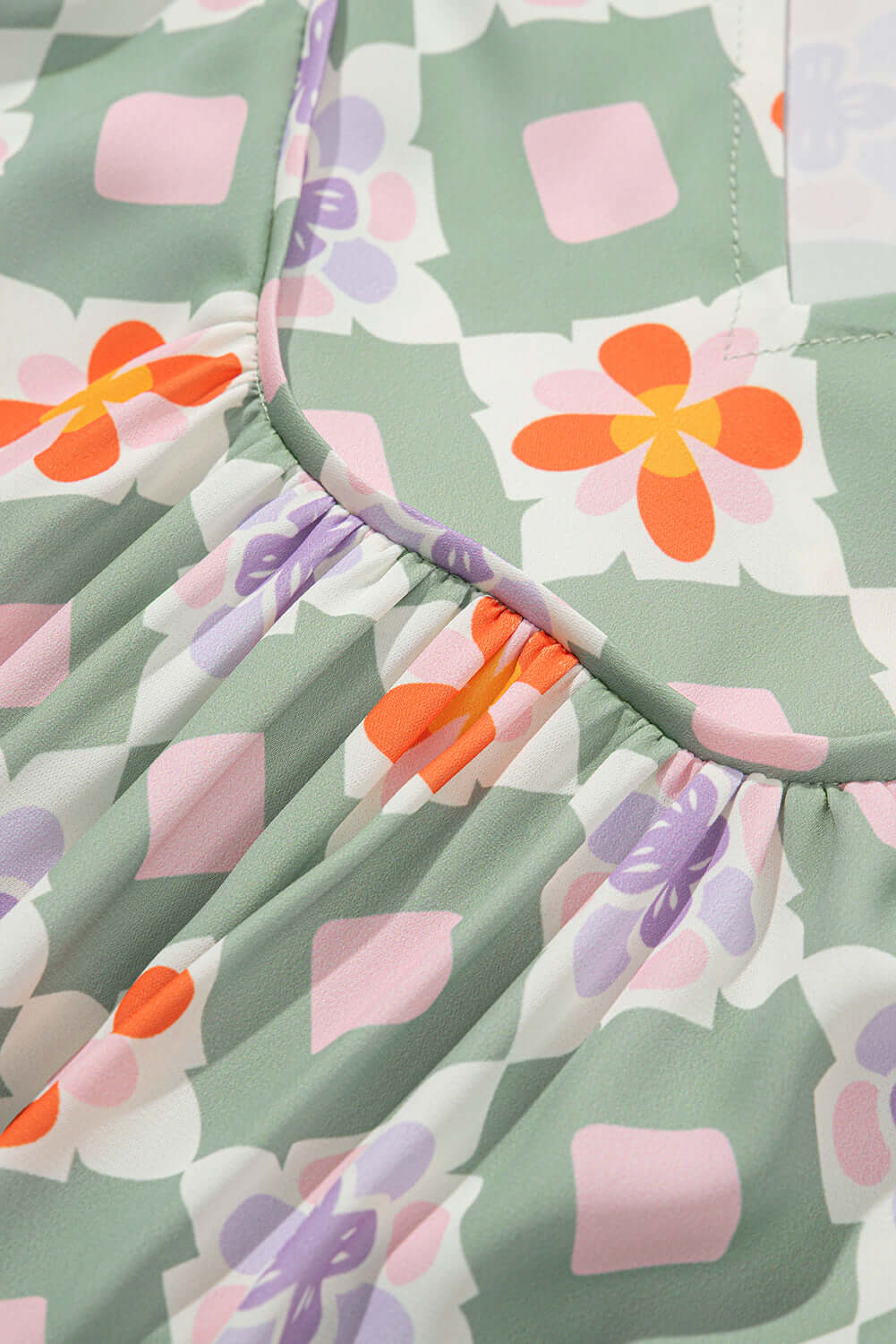 Close-up of Mint Mosaic Dress showing green floral print with colorful geometric shapes and soft fabric texture.