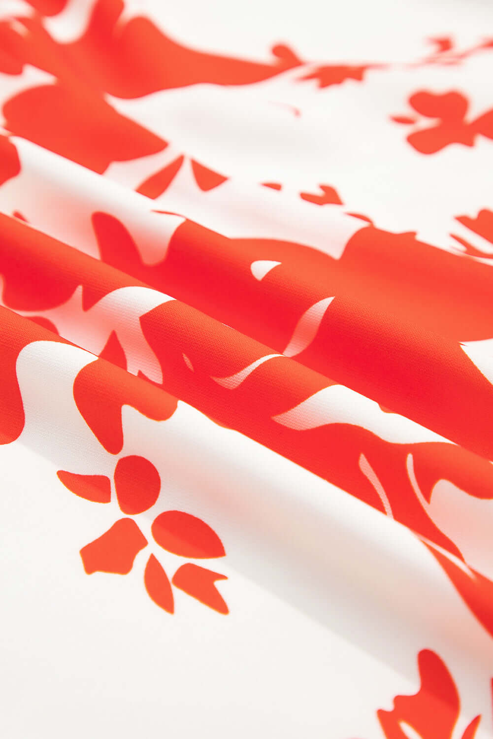 Close-up of red floral print fabric on ivory background, showcasing the Salsa Garden Dress design.