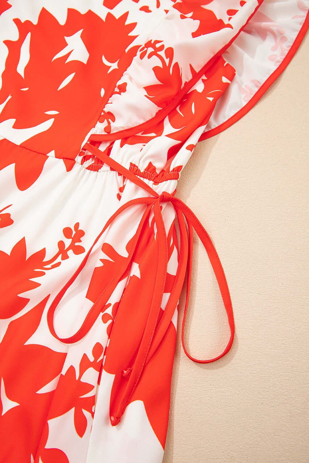Close-up of Salsa Garden Dress with red floral print and elegant tie detail on the waist.