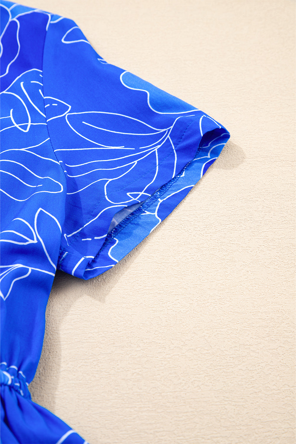 Close-up of the Blue Crush Dress with vibrant blue fabric and floral pattern, showcasing elegant short sleeves.