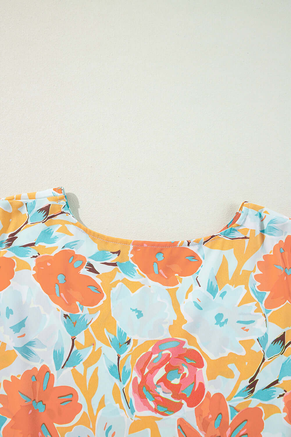 Vibrant tangerine floral print top featuring oversized blooms in coral, pink, and mint colors.