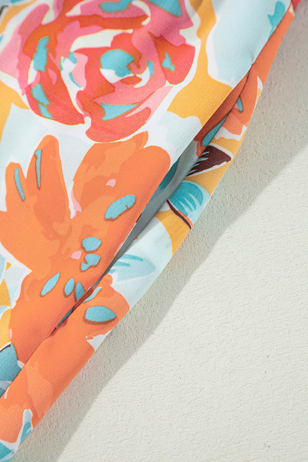 Close-up of vibrant tangerine floral fabric, featuring oversized blooms in coral, pink, and mint—ideal for a stylish outfit.