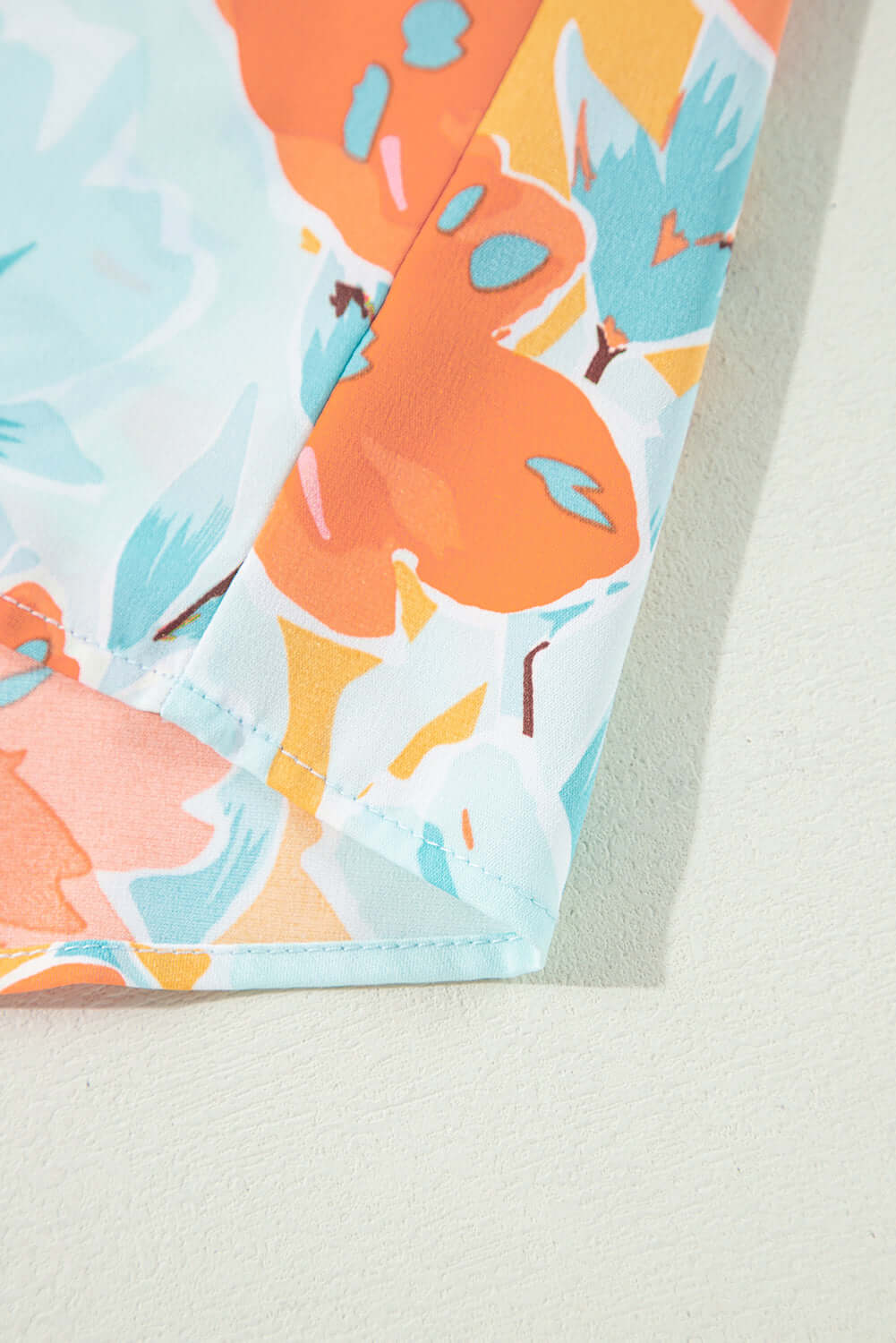 Close-up of vibrant tangerine floral print fabric from Sunset Stroll Pants Set, showcasing bold oversized blooms.