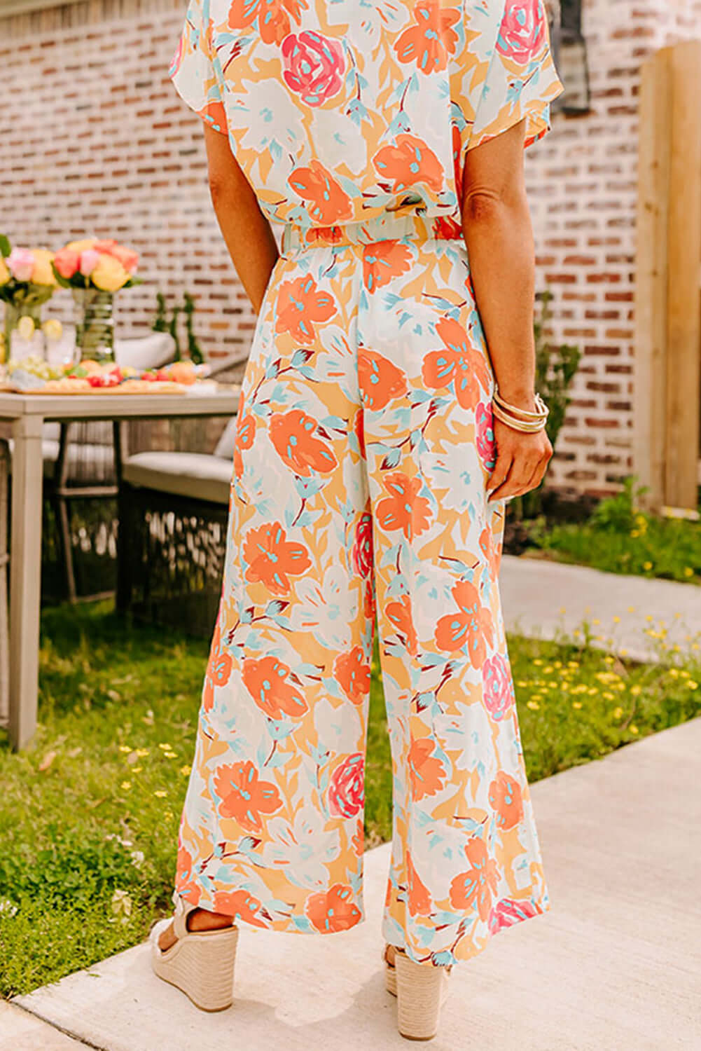 Model showcasing Sunset Stroll Pants Set with vibrant floral print under sunny outdoor setting.