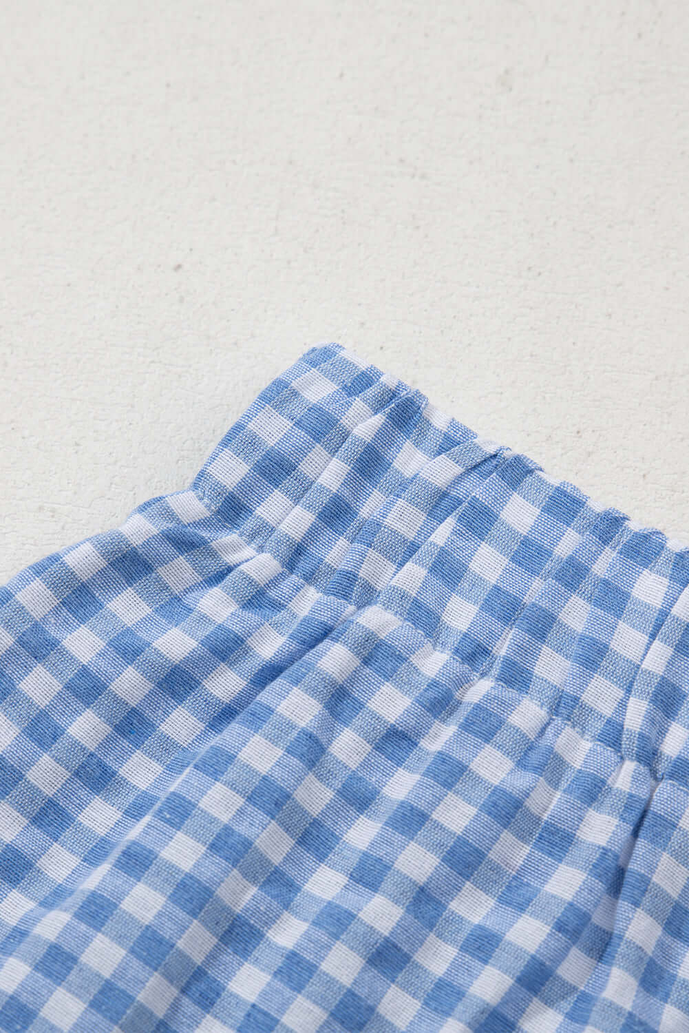 Close-up of blue gingham fabric for Picnic Perfect Shorts showcasing elastic waistband design.