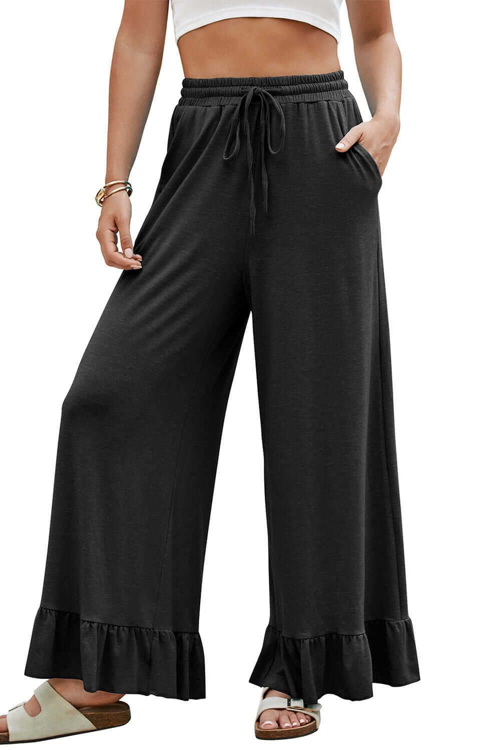 Model wearing CHARMED COMFORT WIDE LEG PANTS in black with ruffled hem and high waist for stylish comfort.