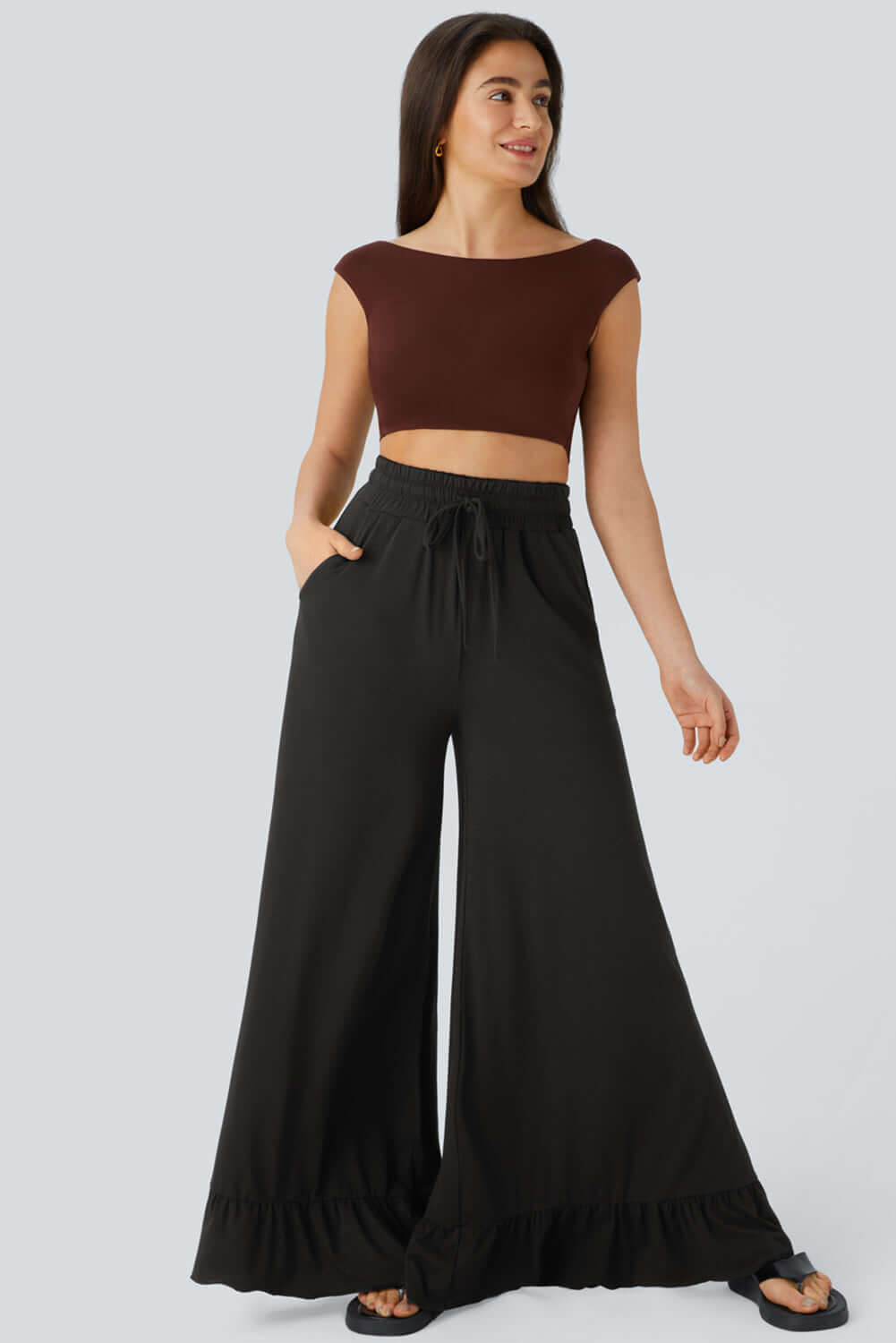 Model showcasing CHARMED COMFORT WIDE LEG PANTS with ruffled hem, high waist, and a flowy silhouette.