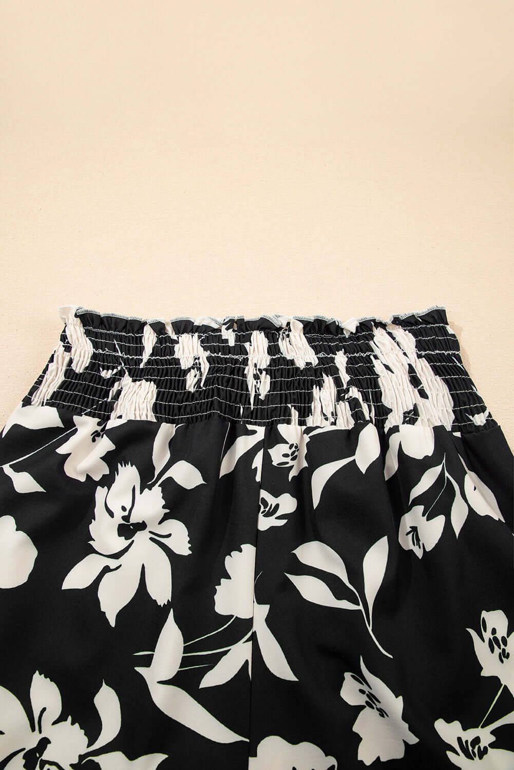 Close-up of the smocked waistband of EVENING OUT WIDE LEG PANTS featuring a black floral print.