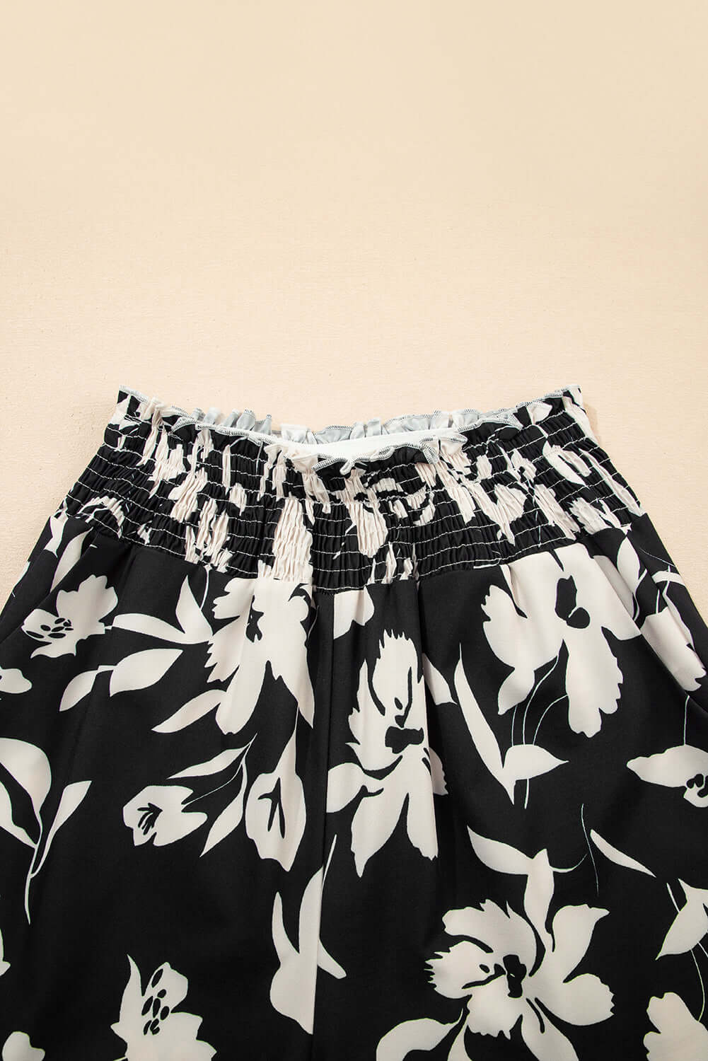 EVENING OUT WIDE LEG PANTS - Close-up of black floral print with smocked high waist detail.