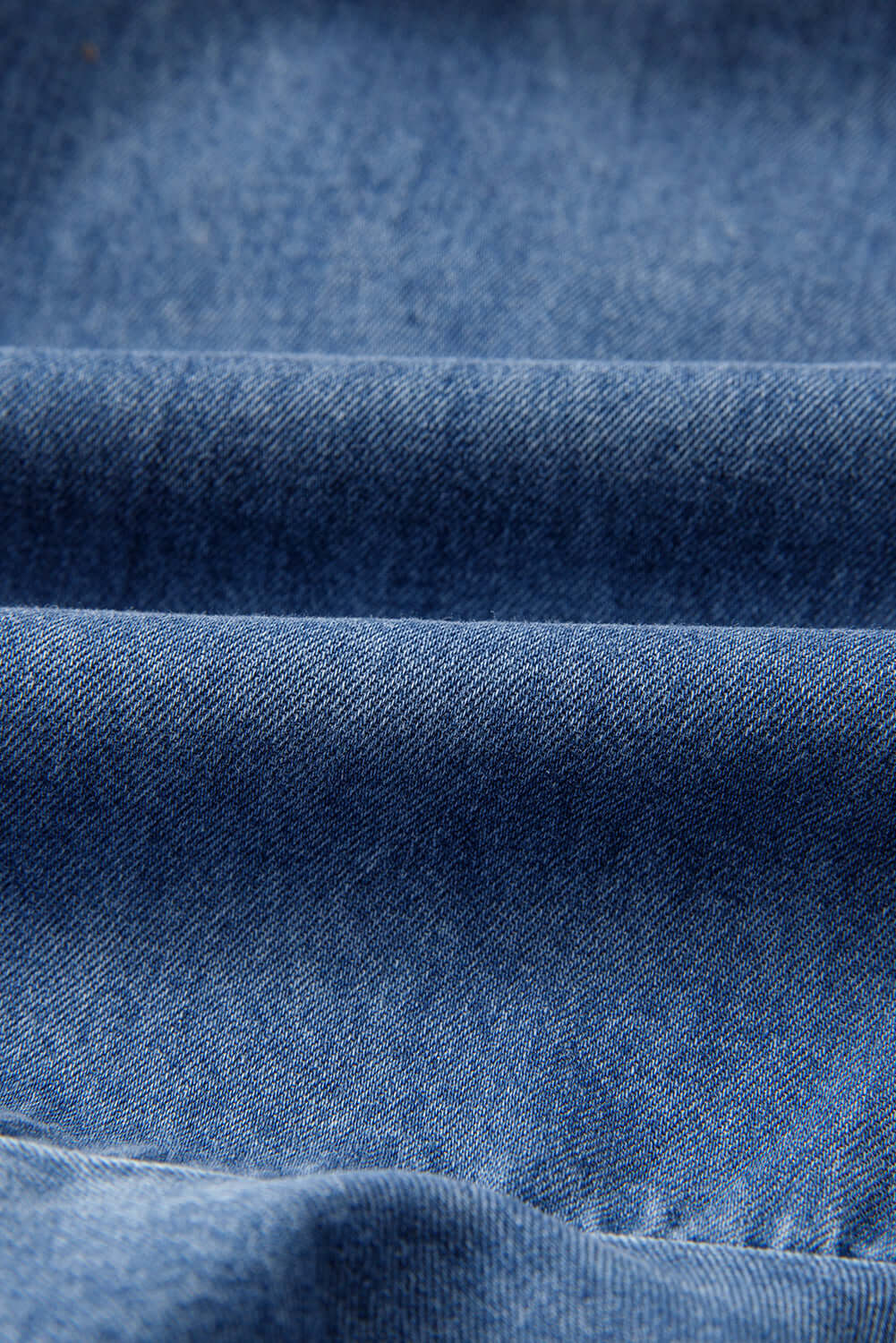 Close-up of soft medium blue denim fabric showcasing its texture and quality for clothing.
