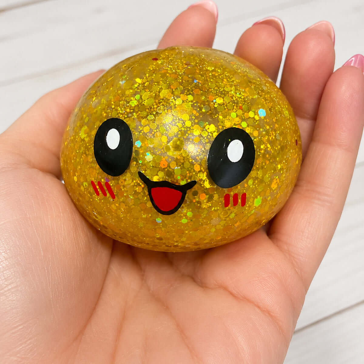 Hand holding a shiny Glitter Orbeez Dumpling Trio character with a smiling face.