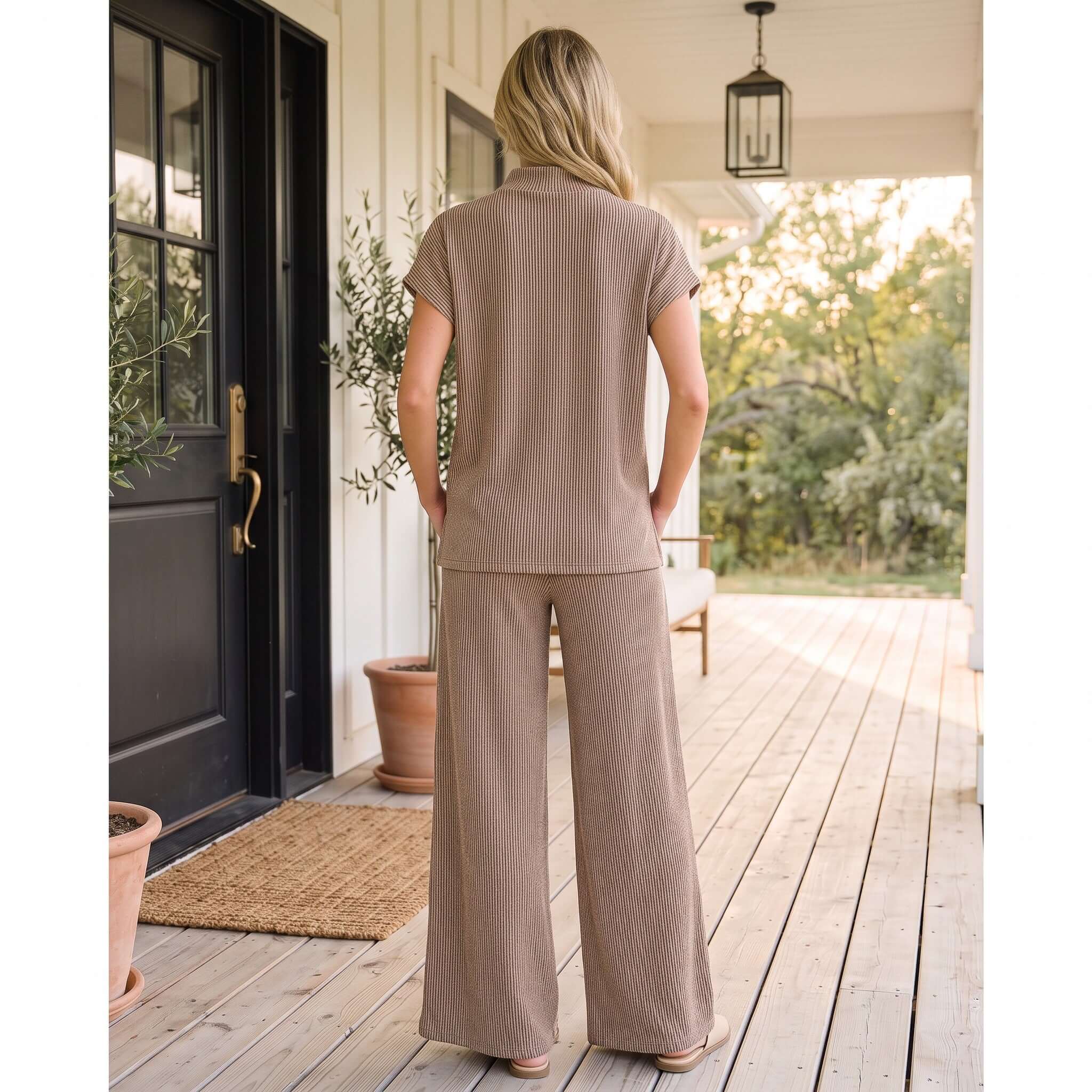 Back view of a woman wearing BONFIRE NIGHTS PANTS SET (cocoa) on a porch, showcasing its cozy and stylish design.