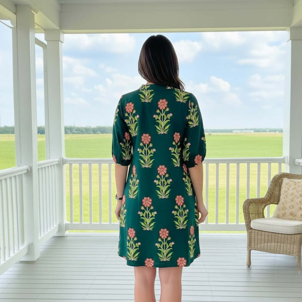 Woman standing in a floral Radiate Confidence Dress, showcasing a vibrant print against a scenic background.